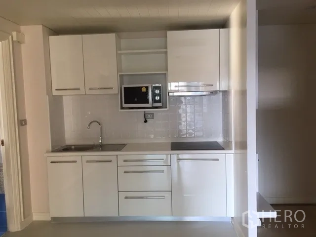 คอนโด ให้เช่าในPathum Wan, Bangkok - ครัวบิลท์อินสีขาวพร้อมตู้เก็บของ อ่างล้างมือ ไมโครเวฟ เตาไฟฟ้า และผนังกระเบื้อง