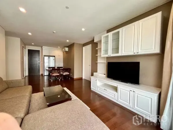 Condominium for rent in Watthana, Bangkok - Open-plan living room facing a white media wall and dining set under recessed lighting.