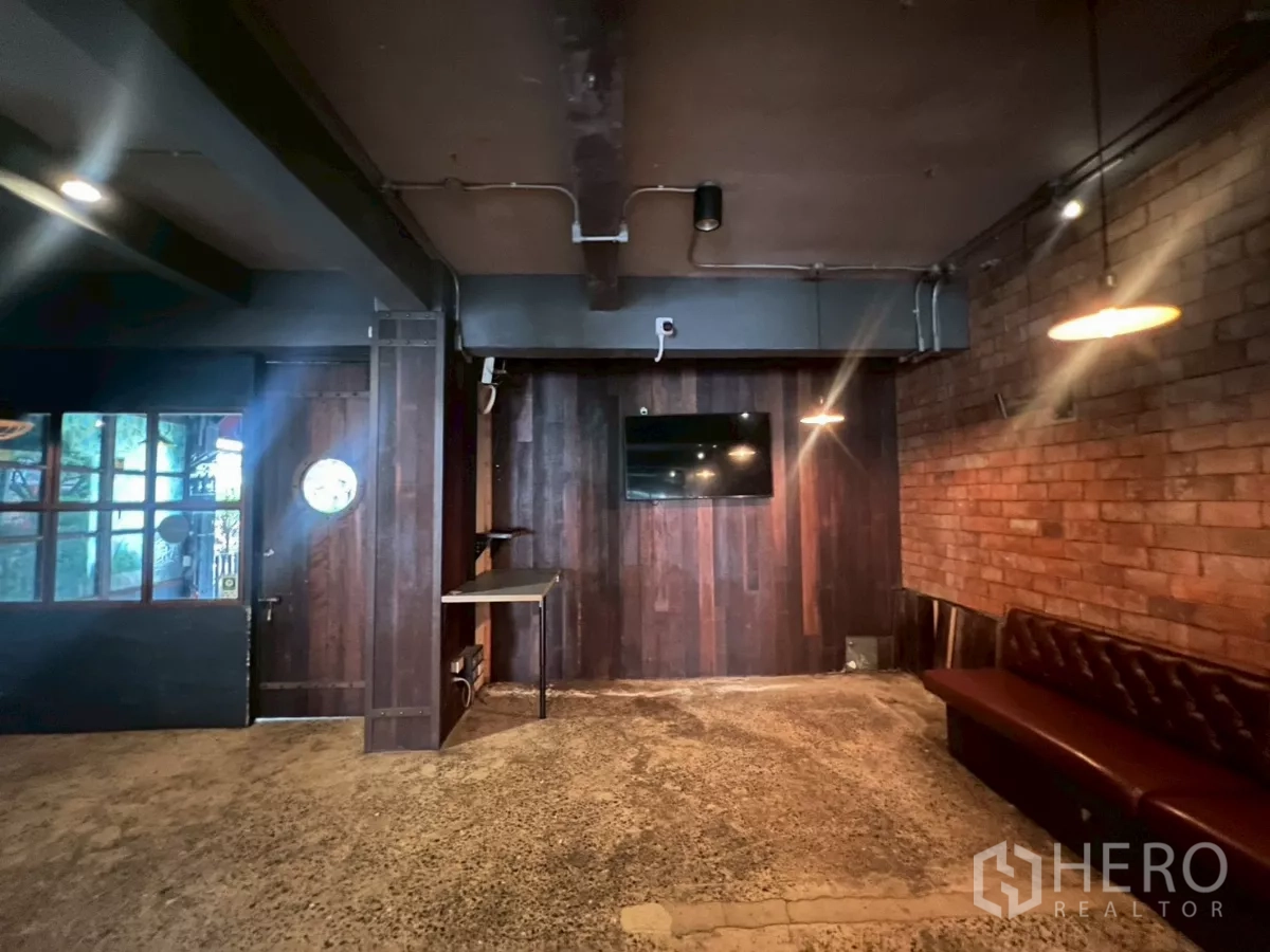 零售空间 出租 - 转角休息区，深色木饰面与外露管线并设电视。