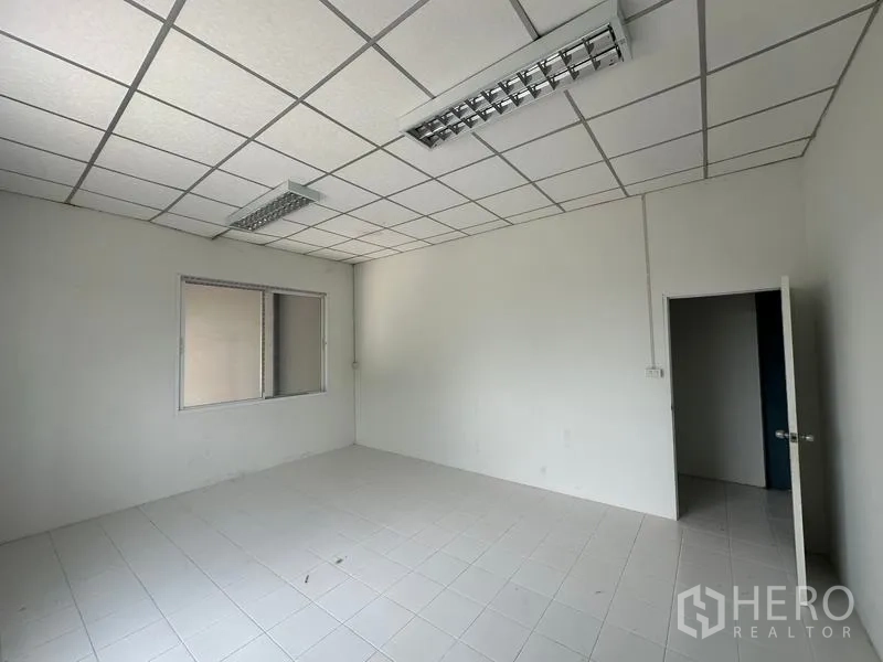 工厂 出租在Bang Bua Thong, Nonthaburi - 整洁的办公房间，方格吊顶、照明与内窗，可眺望生产区。