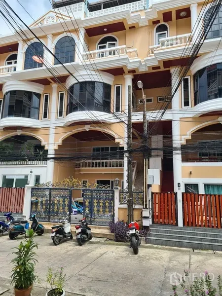 ทาวน์เฮาส์ ให้เช่าในKhlong Toei, Bangkok - ด้านหน้าทาวน์เฮ้าส์หลายชั้น โทนครีม ระเบียงโค้ง และประตูรั้วเหล็ก ใกล้ BTS ทองหล่อ