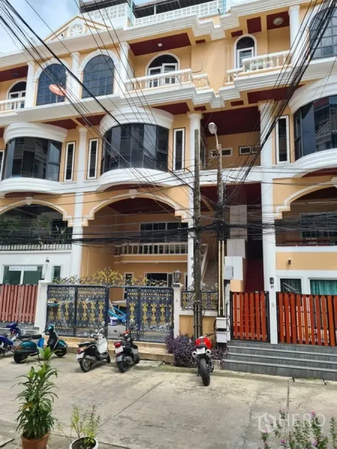 ทาวน์เฮาส์ ให้เช่าในKhlong Toei, Bangkok - ด้านหน้าทาวน์เฮ้าส์หลายชั้น โทนครีม ระเบียงโค้ง และประตูรั้วเหล็ก ใกล้ BTS ทองหล่อ
