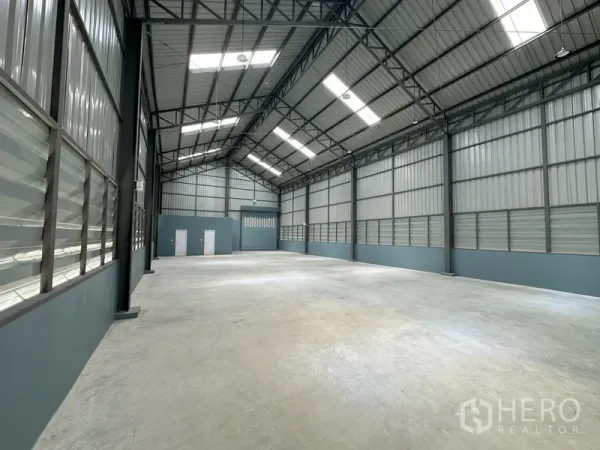 Factory for rent in Khlong Luang, Pathum Thani - Spacious warehouse hall with high steel truss roof, skylights, and polished concrete floor.