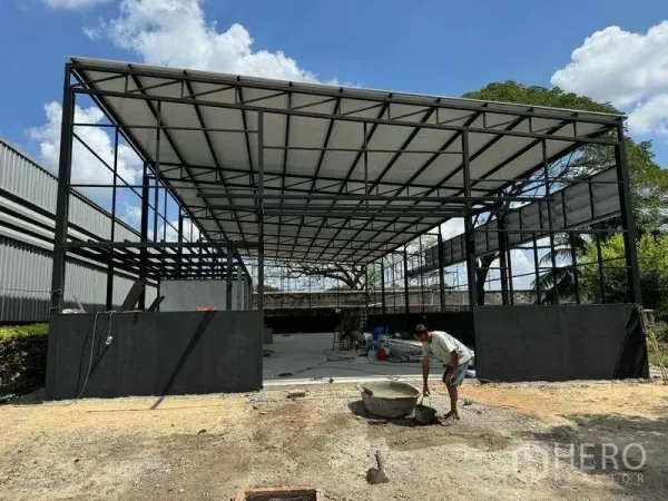 货栈 出租在Mueang Pathum Thani, Pathum Thani - 新建仓库立面，突出高挑雨棚与半高围墙。