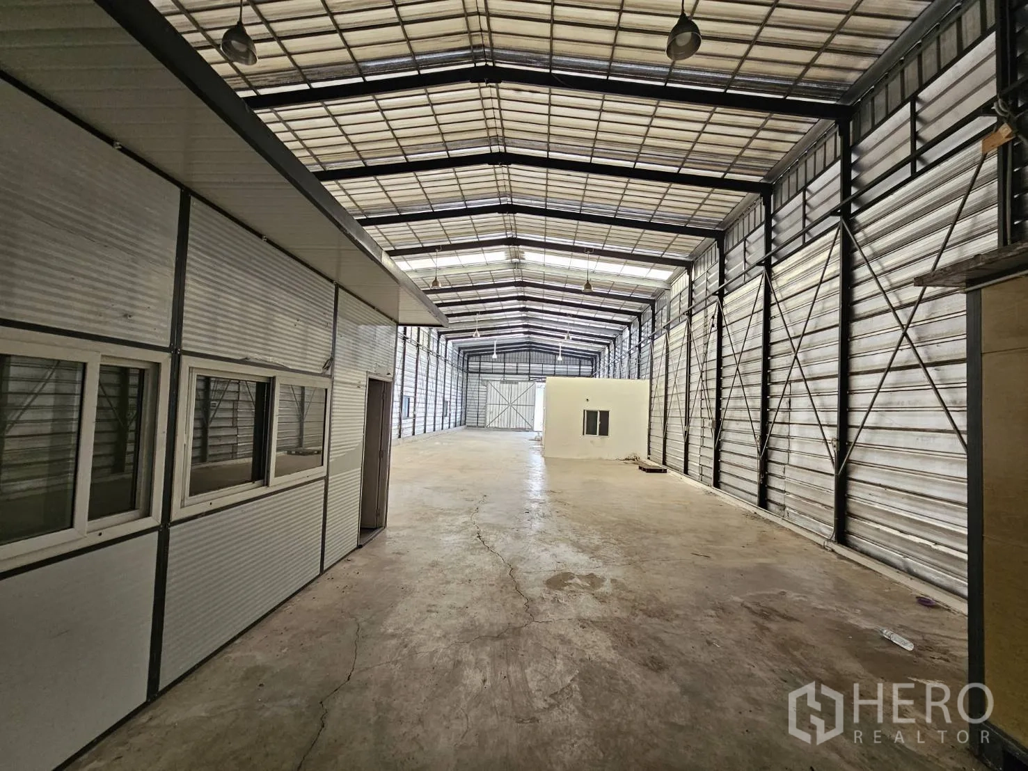 Warehouse for rent in Bang Phli, Samut Prakan - Aisle view beside a modular office under a high roof with hanging lights and steel walls.