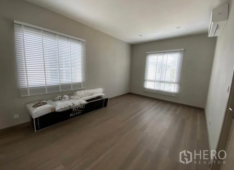 บ้าน ให้เช่า - ห้องนอนโล่ง พื้นไม้ หน้าต่างสองบานพร้อมมู่ลี่ และเครื่องปรับอากาศติดผนัง
