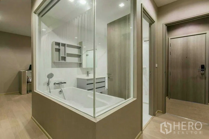 Condominium for rent or sale in Watthana, Bangkok - Glass-partitioned bathroom featuring built-in bathtub and vanity viewed from the hallway.
