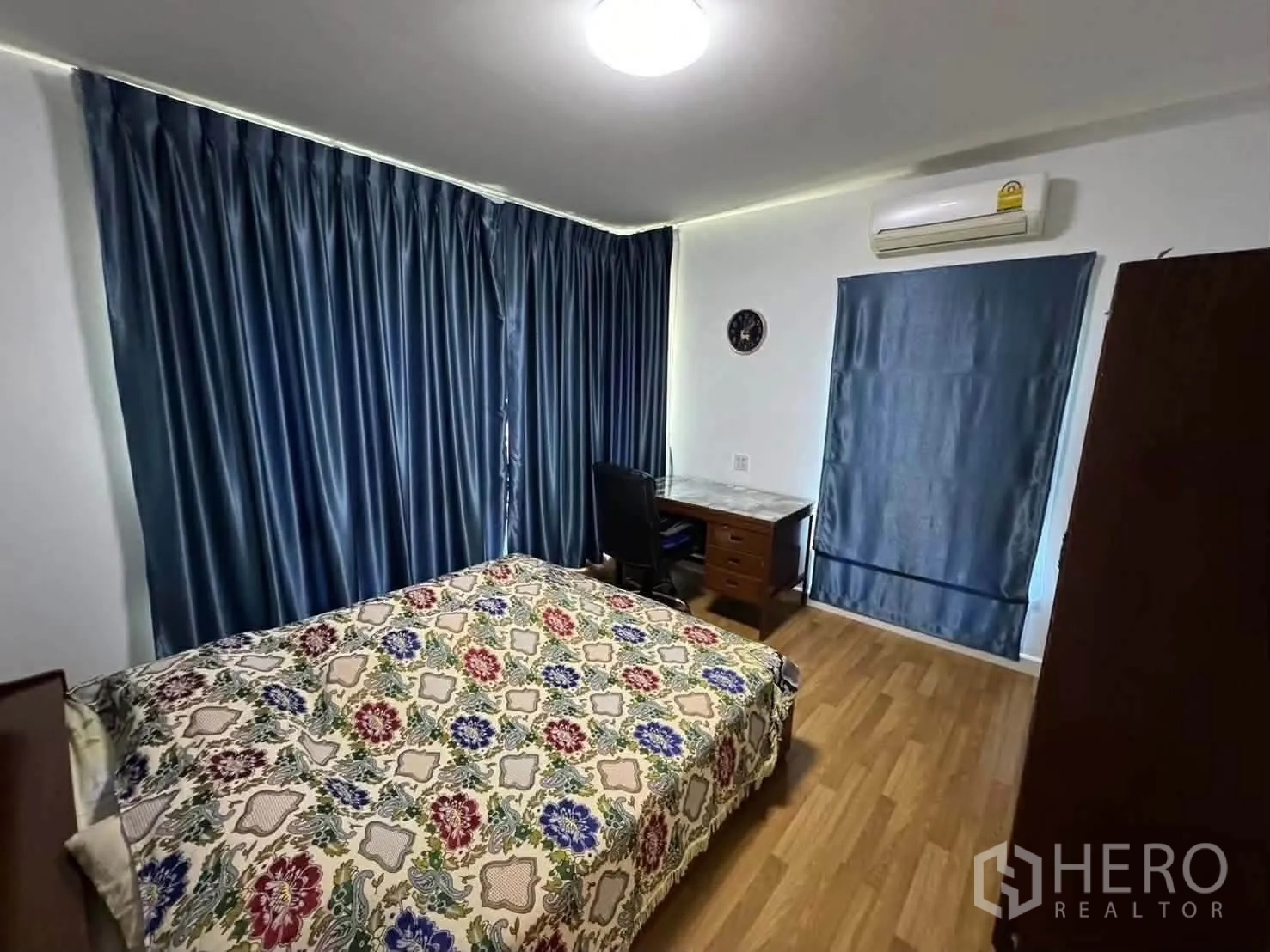 Detached House for rent in Watthana, Bangkok - Bedroom with bed, desk, blue curtains, wood floor, and wall-mounted air conditioner.