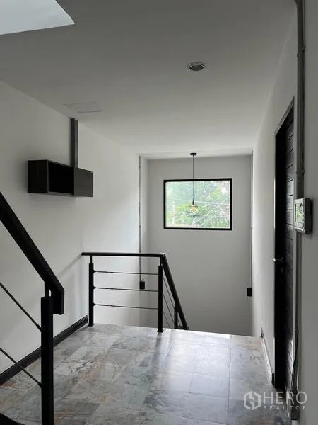 Townhouse for rent in Phaya Thai, Bangkok - Stair landing with metal handrail and picture window bringing in natural light.