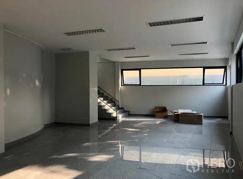 办公空间 出租在Khlong Toei, Bangkok - 开放式办公室内景，石材地面、室内楼梯与长条窗户。