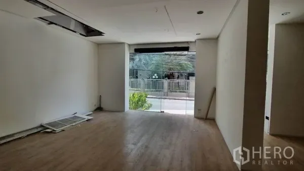 零售空间 出租在Khlong Toei, Bangkok - 一层明亮商铺内景，整面玻璃门头，木纹地板，可见街景。