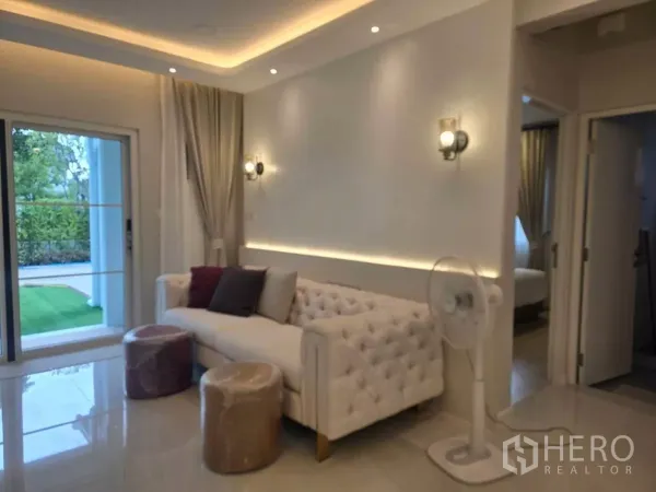 Detached House for rent in Bang Phli, Samut Prakan - Cozy sitting area with tufted sofa, wall sconces and sliding door opening to the garden.