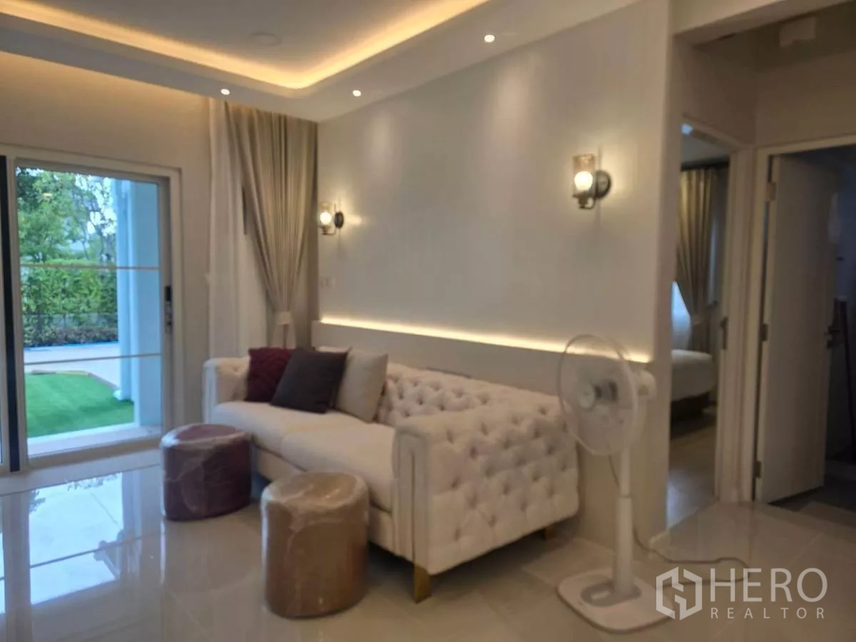 Detached House for rent in Bang Phli, Samut Prakan - Cozy sitting area with tufted sofa, wall sconces and sliding door opening to the garden.