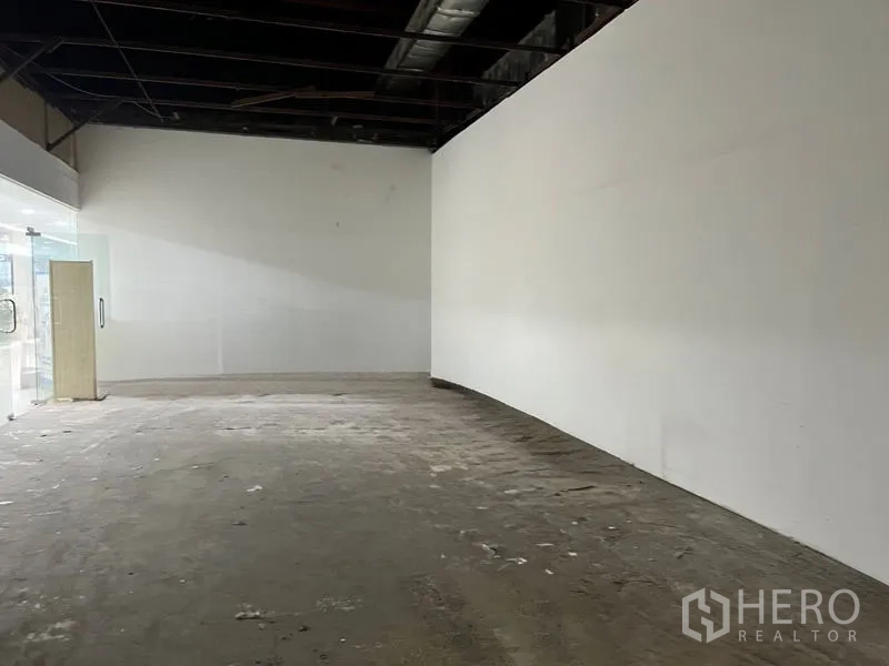 零售空间 出租在Khlong Toei, Bangkok - 深进式商铺，长弧形白墙与原始地面。