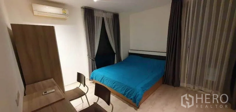 Detached House for rent in Prawet, Bangkok - Bright bedroom with blue bedding, desk, and wall-mounted air conditioner.