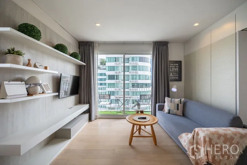 Condominium for rent in Watthana, Bangkok - Sofa lounge opening to a balcony with city skyline views through floor-to-ceiling glass.