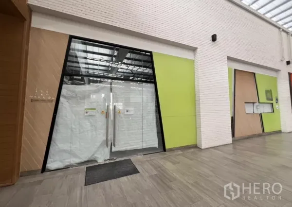 พื้นที่ขายปลีก ให้เช่าในKhlong Toei, Bangkok - หน้าร้านกระจกบานใหญ่ในคอมมูนิตี้มอลล์ โถงทางเดินสมัยใหม่ โทนสีเขียวและหลังคากระจกโปร่งแสง.