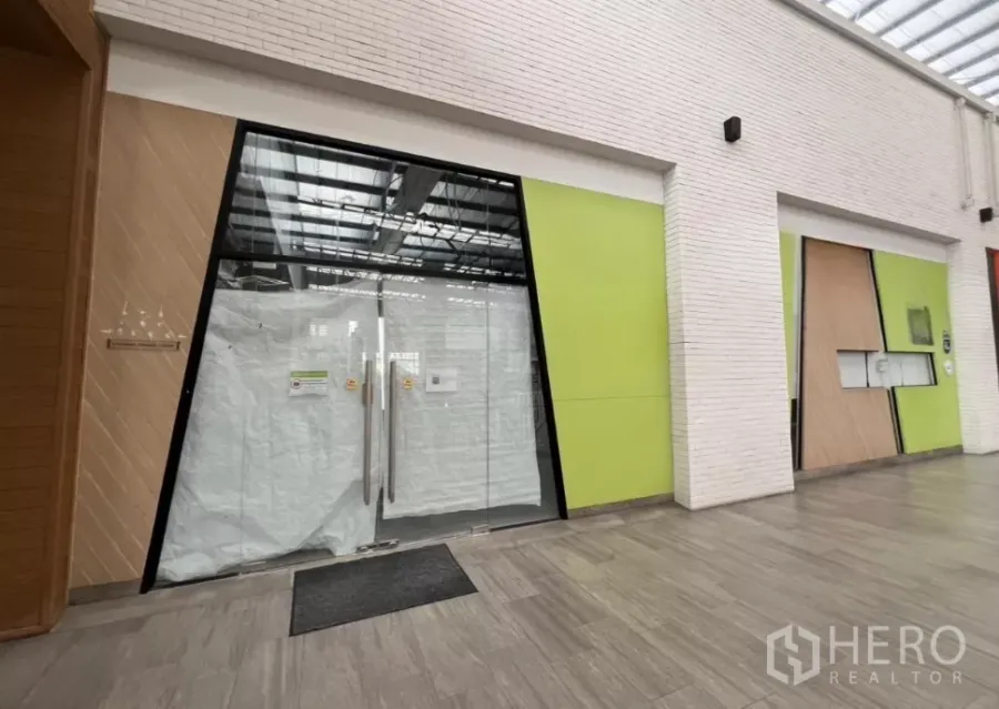 พื้นที่ขายปลีก ให้เช่าในKhlong Toei, Bangkok - หน้าร้านกระจกบานใหญ่ในคอมมูนิตี้มอลล์ โถงทางเดินสมัยใหม่ โทนสีเขียวและหลังคากระจกโปร่งแสง.