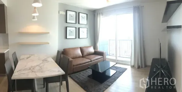 คอนโด ให้เช่าในKhlong Toei, Bangkok - ห้องนั่งเล่นมีโซฟาหนัง ประตูกระจกออกระเบียง พรม และชั้นวางทีวี ในคอนโดสไตล์โมเดิร์นย่านสุขุมวิท