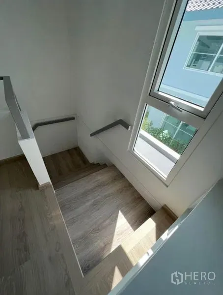 บ้าน ให้เช่าในMin Buri, Bangkok - บันไดพื้นไม้พร้อมหน้าต่างสูง รับแสงธรรมชาติสู่โถงบันได