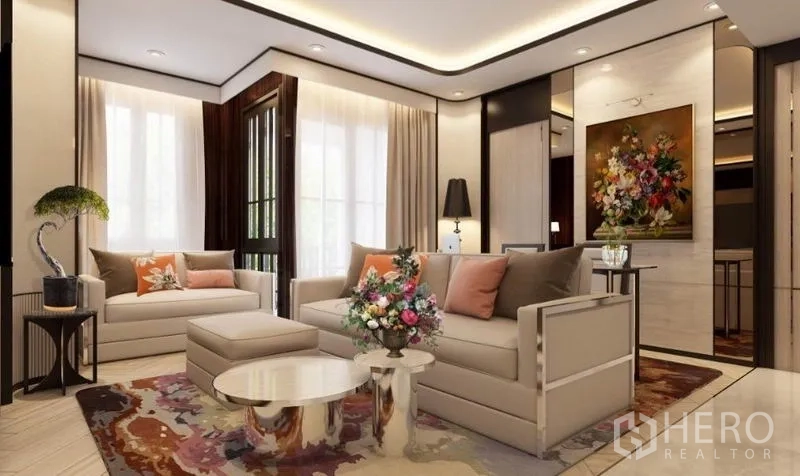 公寓 出租在Watthana, Bangkok - 明亮客厅，双沙发、花卉地毯、圆形茶几与通往阳台的玻璃门和装饰画。