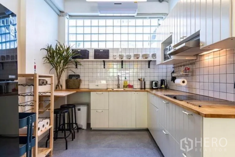 Townhouse for rent in Pathum Wan, Bangkok - Modern white kitchen with wood countertops, tile backsplash and open shelving.