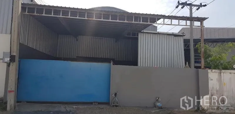 货栈 出租在Bang Phli, Samut Prakan - 仓库外立面，宽大的蓝色推拉大门与带顶入口，位于邦普里。