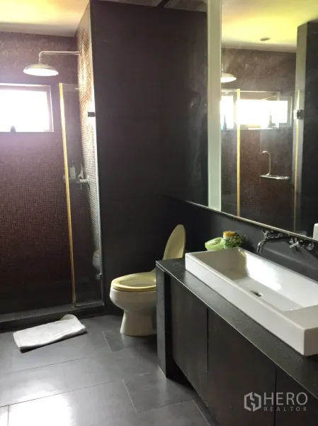 Condominium for rent in Watthana, Bangkok - Modern bathroom with long rectangular vanity, toilet and glass walk‑in shower with mosaic tiles.
