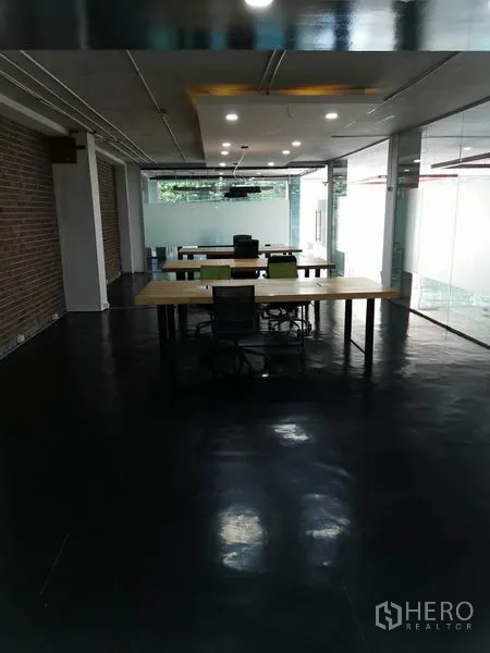 办公空间 出租在Khlong Toei, Bangkok - 开放工位区，公共长桌、筒灯与玻璃隔断。