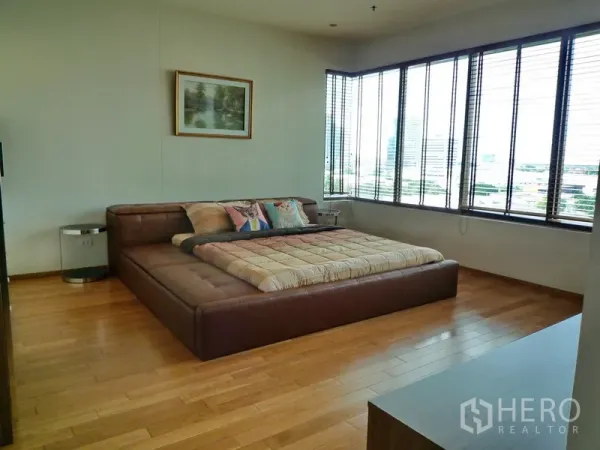 คอนโด ให้เช่าในKhlong Toei, Bangkok - ห้องนอนมาสเตอร์กว้าง เตียงแพลตฟอร์มหุ้มหนัง พื้นไม้ และหน้าต่างมุมมองเมือง