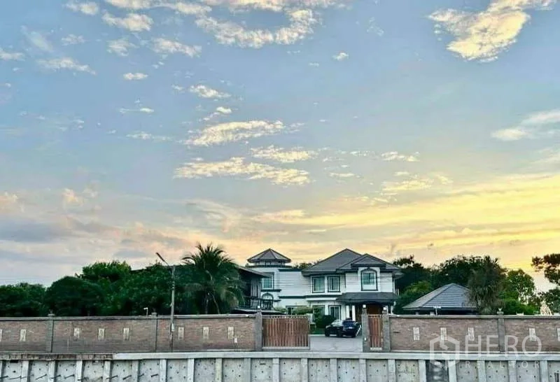 บ้าน ขายในKhlong Luang, Pathum Thani - มุมมองกว้างของบ้านและกำแพงรั้วจากอีกฝั่งของคลองในช่วงพระอาทิตย์ตก