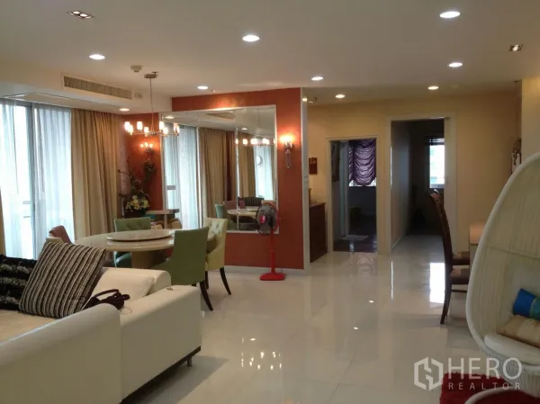 公寓 出租在Bang Rak, Bangkok - 明亮的客餐厅一体空间，配有沙发、圆餐桌、枝形吊灯和落地窗帘。