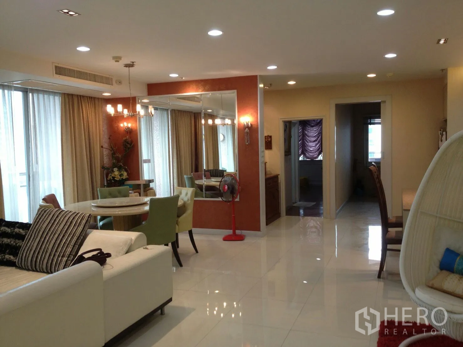 公寓 出租在Bang Rak, Bangkok - 明亮的客餐厅一体空间，配有沙发、圆餐桌、枝形吊灯和落地窗帘。