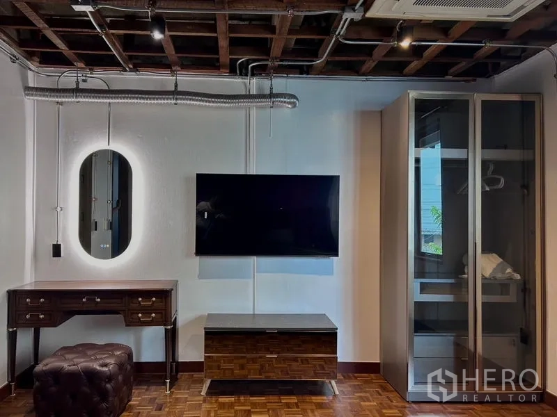 Apartment for rent in Khlong Toei, Bangkok - Entertainment wall with flat-screen TV, backlit mirror and glass wardrobe.