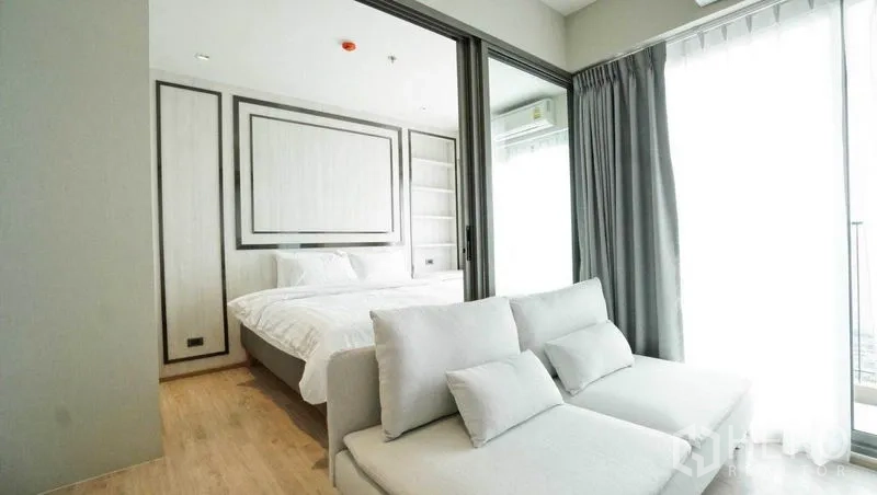 คอนโด ขายในKhlong Toei, Bangkok - ห้องนั่งเล่นและห้องนอนกั้นด้วยประตูกระจกบานเลื่อน โซฟาสีอ่อน และหน้าต่างสูง