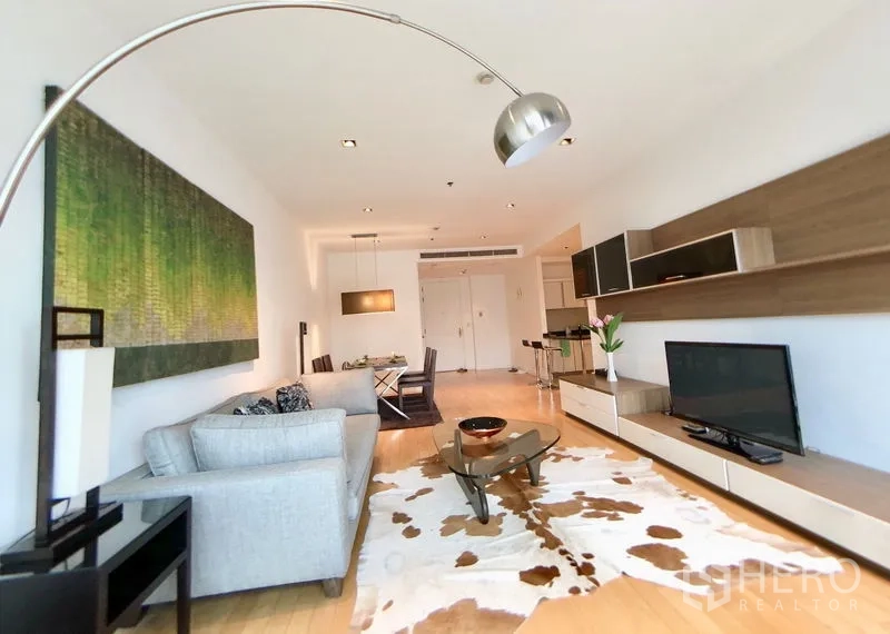 Condominium for rent in Pathum Wan, Bangkok - Bright living and dining area with large artwork, sofa, media console and cowhide rug.