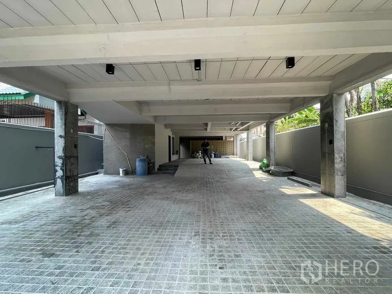 Home Office for rent in Phaya Thai, Bangkok - Covered ground-floor parking area under the building with concrete columns and tiled driveway.