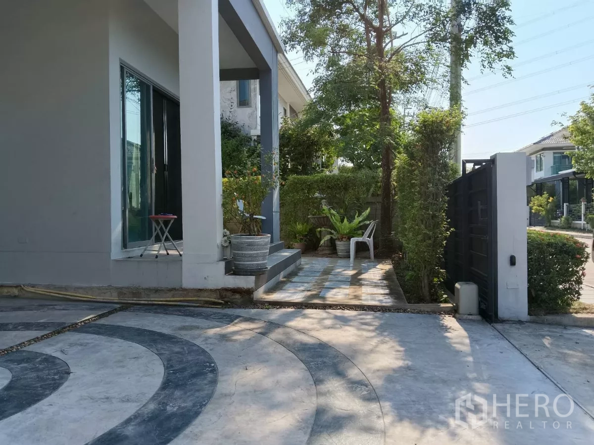 บ้าน ขายในLat Krabang, Bangkok - เฉลียงหน้าบ้านและทางรถเข้าบ้าน ข้างแนวไม้พุ่มและประตูรั้ว