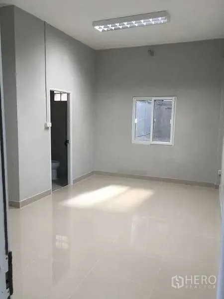 Warehouse for rent in Mueang Samut Prakan, Samut Prakan - Sunlit office room with window and doorway to an en-suite restroom.