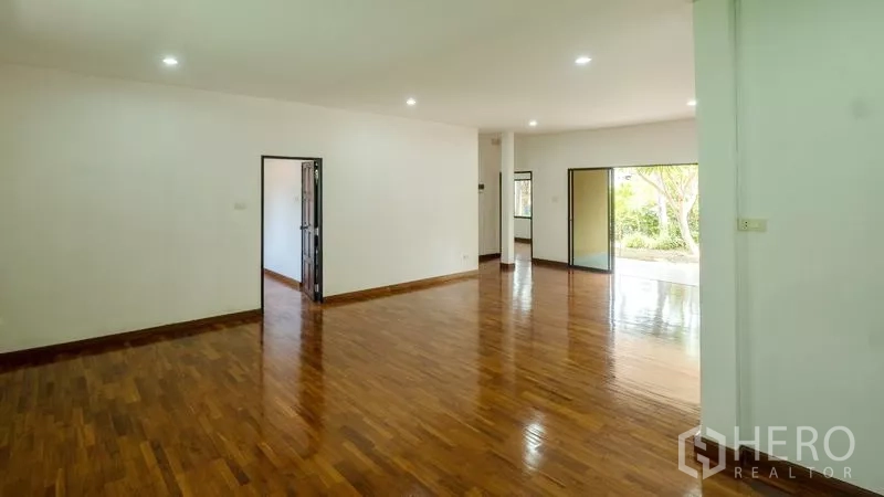 Detached House for sale in Bang Lamung, Chon Buri - Spacious lounge with polished wooden flooring and recessed lighting facing the garden.