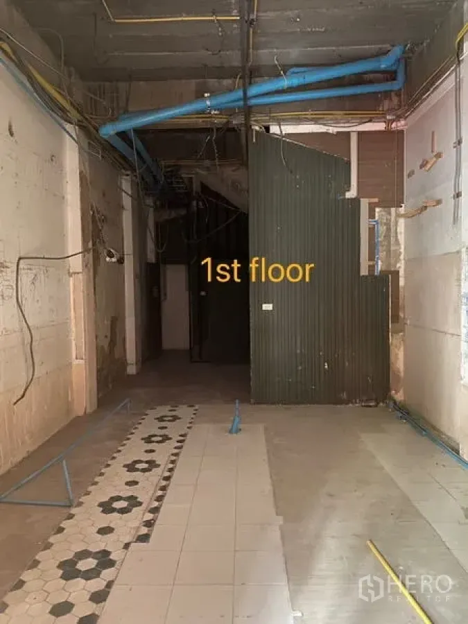 Shophouse for rent in Bang Rak, Bangkok - Ground-floor shophouse interior with high ceiling, exposed pipes and a tiled entry strip