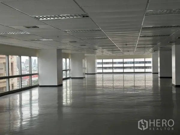 Office Space for rent - Large open‑plan office floor with windows on two sides, grid ceiling lights and city view in Watthana, Bangkok.
