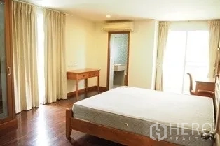 Condominium for rent in Pathum Wan, Bangkok - Spacious bedroom with balcony doors, air conditioner and built-in wardrobe.
