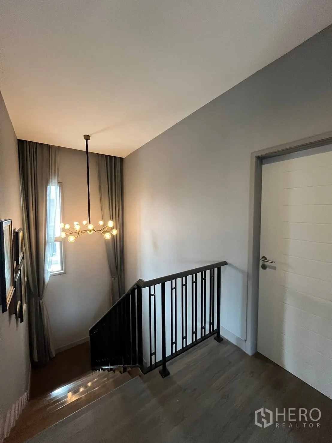 独栋房屋 for rent or sale in Bueng Kum, Bangkok - 楼梯平台带黑色金属栏杆与造型吊灯。