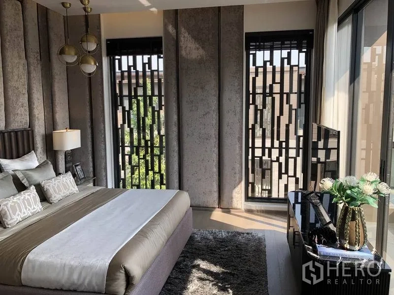 独立式住宅 出售在Bang Kapi, Bangkok - 次卧设纹理墙板、吊灯、几何格栅窗与地毯。