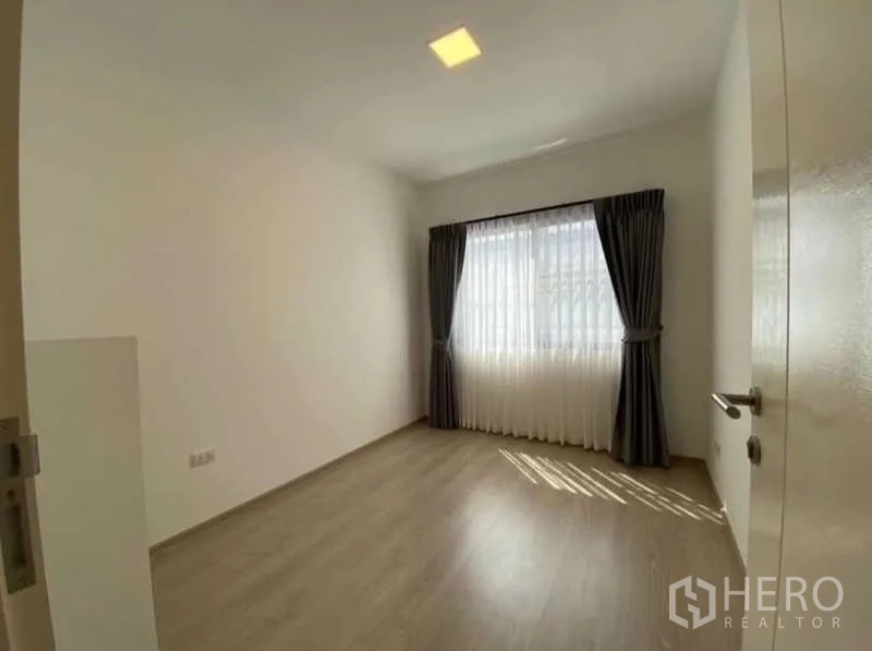 Townhouse for rent in Bang Phli, Samut Prakan - Third bedroom or study with large window, blackout curtains and wood flooring.