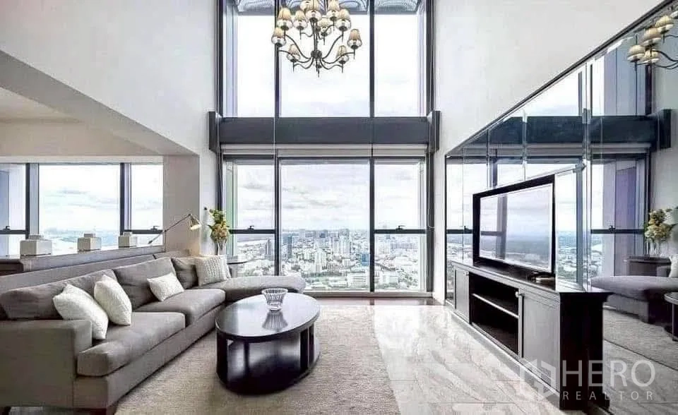 Condominium for rent in Sathon, Bangkok - Media area with towering windows, chandelier and TV console reflecting sweeping city views.