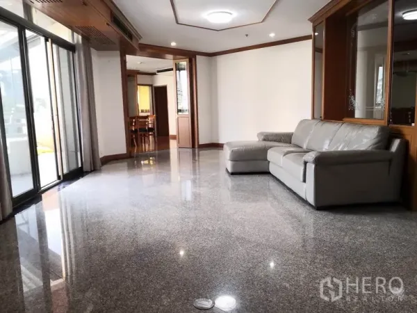 公寓 出租在Khlong Toei, Bangkok - 明亮客厅，抛光石材地面，L型皮沙发，嵌灯与通向阳台的推拉落地门