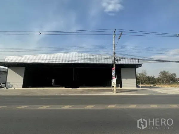 คลังสินค้า ให้เช่าในLam Luk Ka, Pathum Thani - ด้านหน้าโกดังมีช่องเปิดขนาดใหญ่สองช่องและลานเทคอนกรีตติดถนนใหญ่