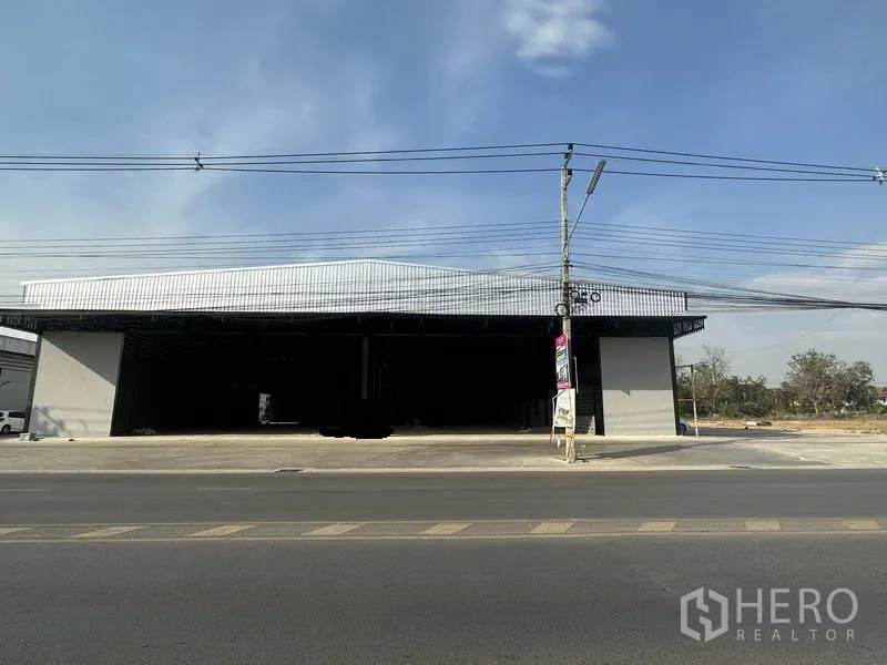 คลังสินค้า ให้เช่าในLam Luk Ka, Pathum Thani - ด้านหน้าโกดังมีช่องเปิดขนาดใหญ่สองช่องและลานเทคอนกรีตติดถนนใหญ่